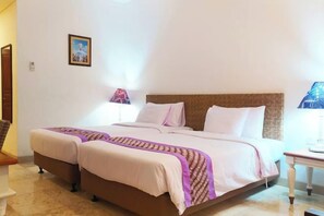 A hotel room with a large bed, two bedside tables, and a lamp. - Puri Lovina Hotel (Bali)