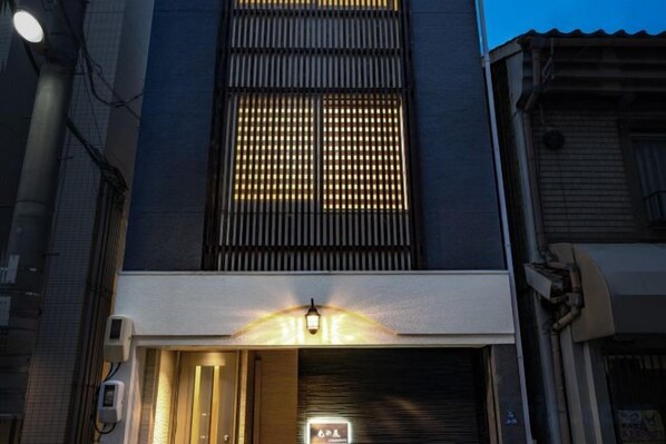 Um edifício com entrada iluminada e uma grande janela com padrão de grade.