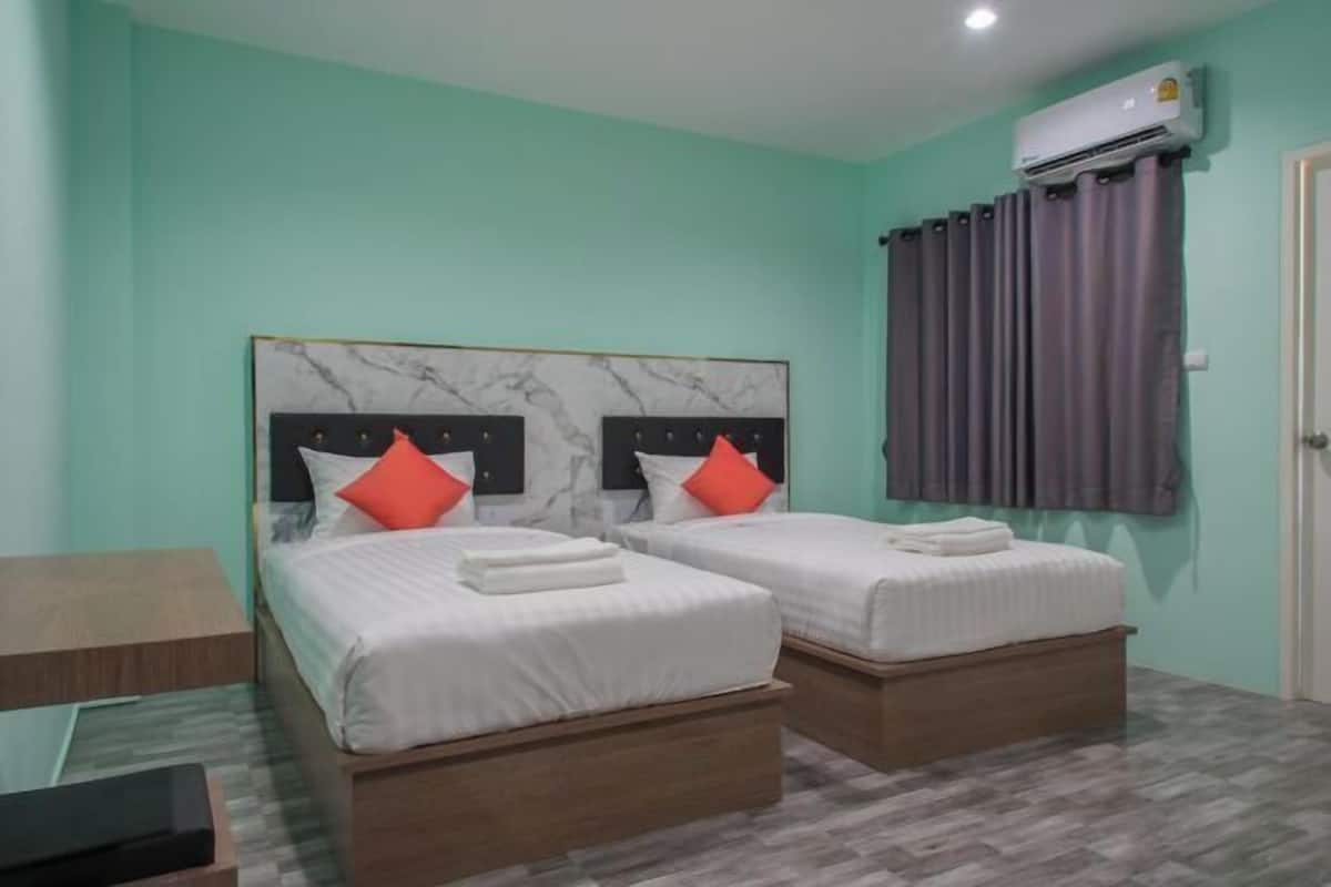 Une chambre avec deux lits, une tête de lit en marbre et un appareil de climatisation.