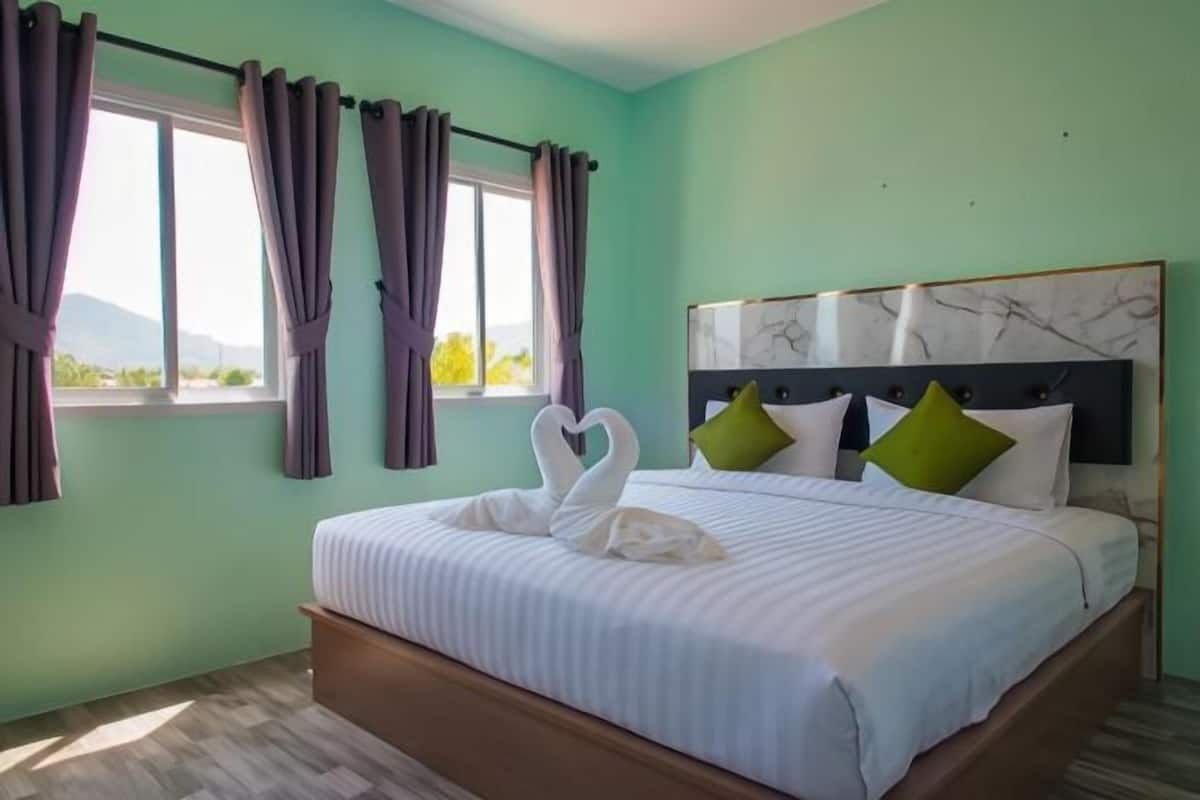 Une chambre à coucher avec un lit, une tête de lit et des rideaux.