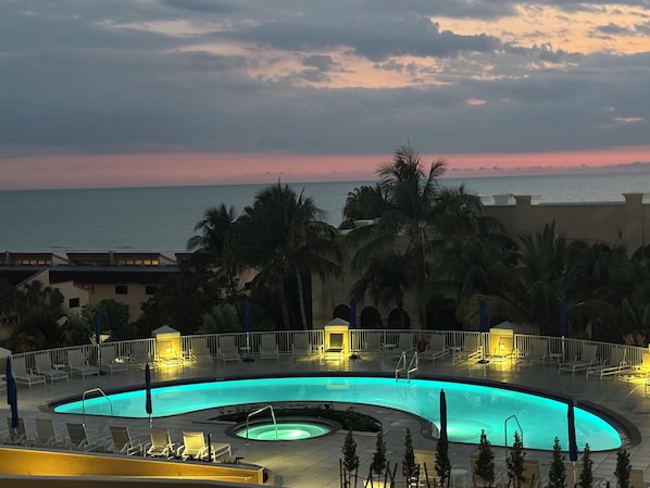 A pool area with lounge chairs, a circular pool, and a view of the ocean at sunset. - Marco Beach Ocean Resort beautiful 8th floor 2 BR beach condo overlooking Gulf (Marco Island)