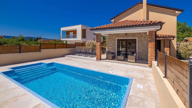 A modern two-story house with a swimming pool, outdoor seating, and a stone facade. - Semi-detached holiday house DIVNA with private pool (Pinezići)