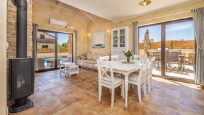 A spacious living area with a fireplace, a dining table, and a sofa. - Semi-detached holiday house DIVNA with private pool (Pinezići)