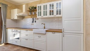A kitchen with white cabinets, a wooden countertop, a built-in oven, and a sink. - Semi-detached holiday house DIVNA with private pool (Pinezići)