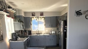 Una cucina compatta con mobili grigi, un forno a microonde integrato, un fornello e un frigorifero.