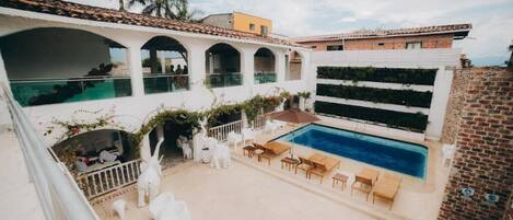 A rooftop pool area with white chairs and a small pool.