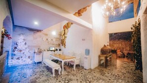A dining area with a wooden table and chairs, a bench, and a chandelier. - Angel de Santa Fe by Bernalo Hotels (Santa Fe de Antioquia)