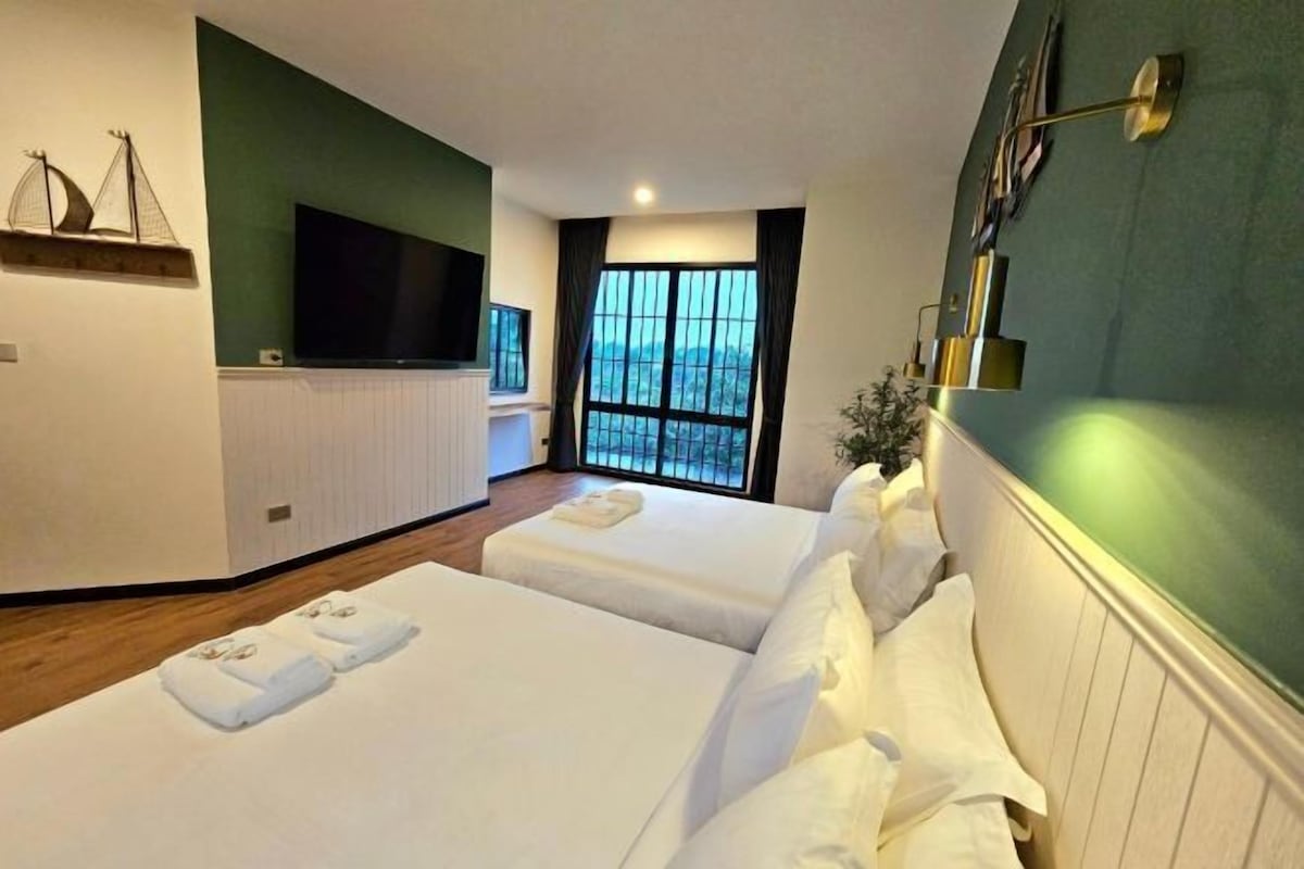 Een hotelkamer met twee bedden, een televisie, een raam met uitzicht en een groene wand.