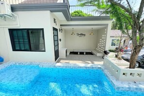 A swimming pool with a tiled deck, a covered seating area, and a wall with a sign. - Brittany Private Pool Villa-Pattaya (Sattahip)