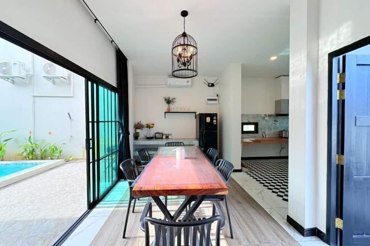 A modern interior with a dining area, kitchen, and a pool view.