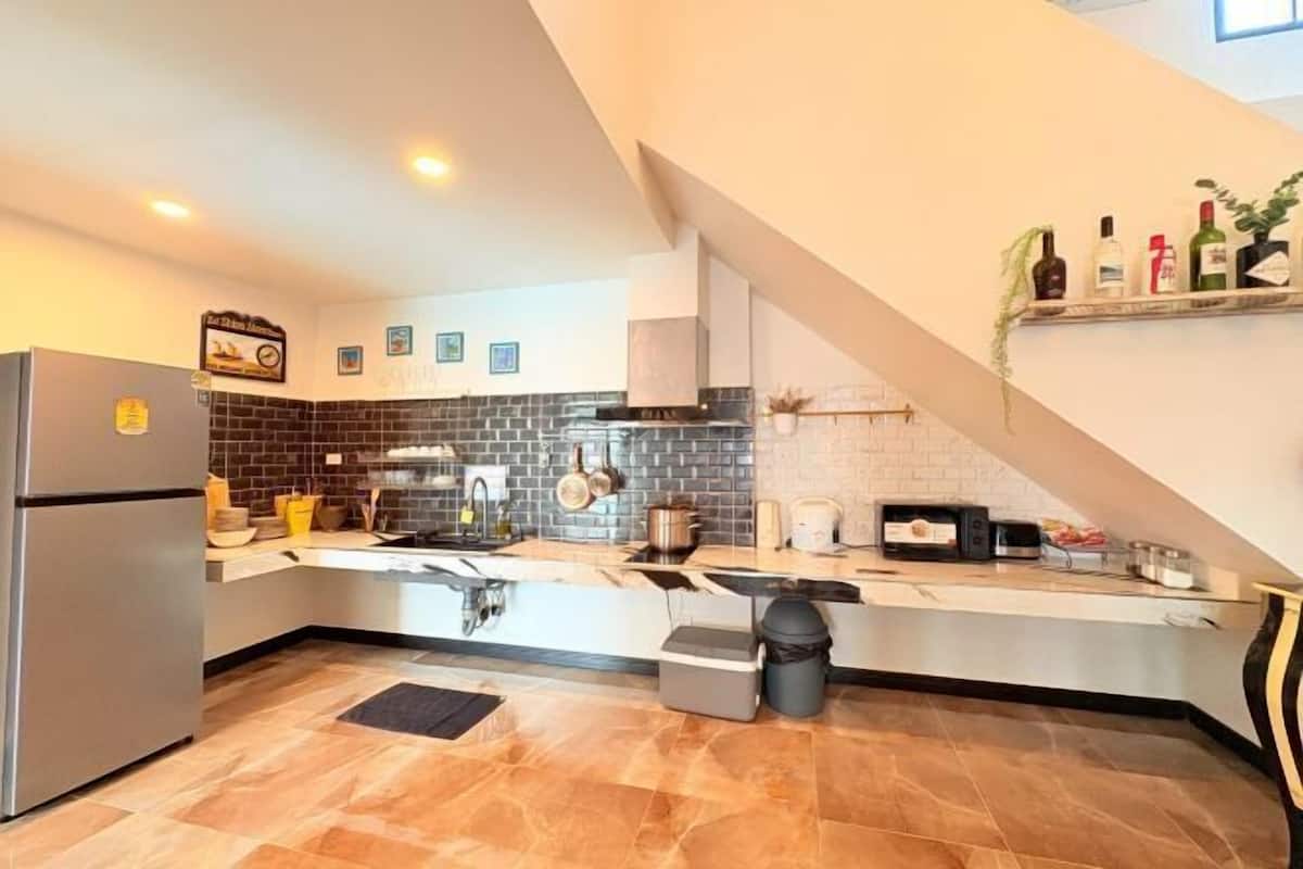 A modern kitchen with a stainless steel refrigerator, a brick backsplash, and a white countertop.