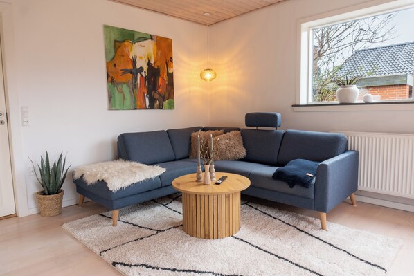 Un salon moderne avec un canapé bleu, une table basse ronde en bois et un tableau accroché au mur.