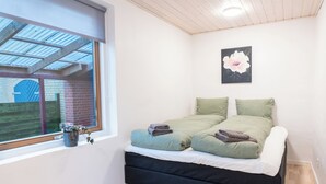 A bedroom with a bed, a window with a view, and a flower painting on the wall. - Villa Holstebro (Holstebro)