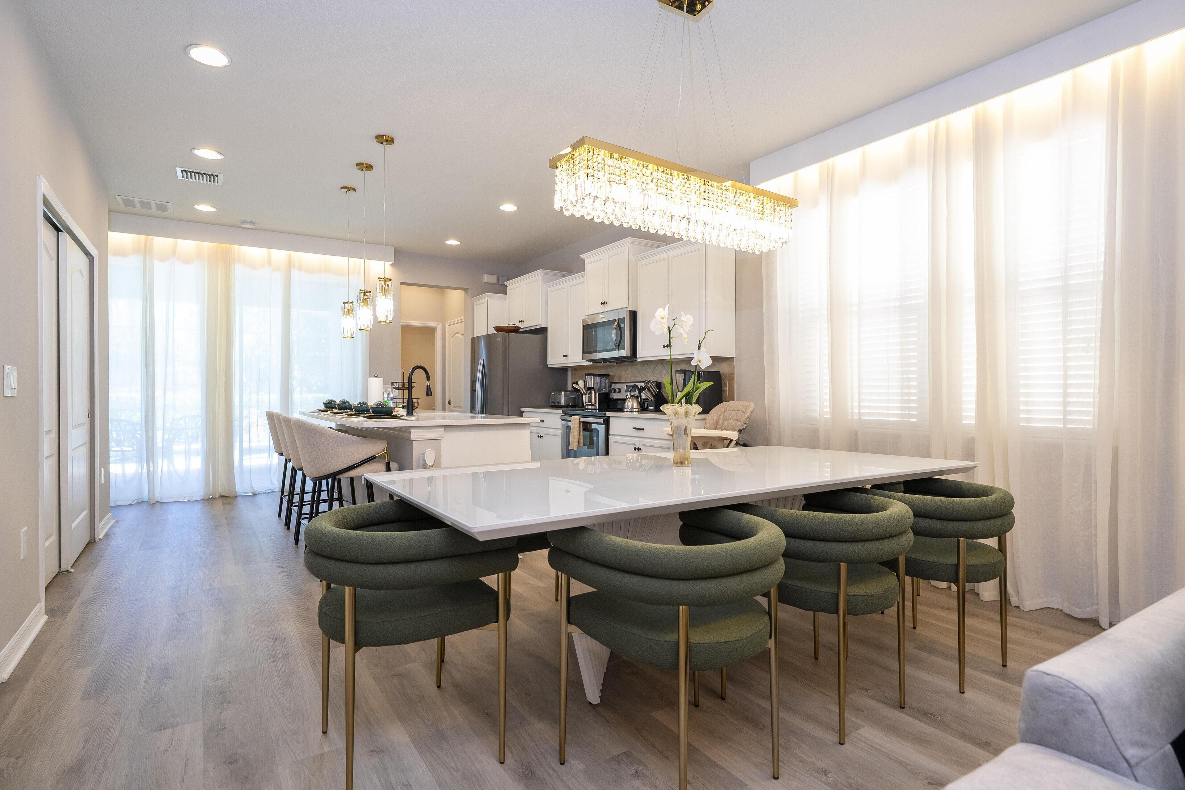 A modern kitchen with a central island, white cabinets, and a chandelier.