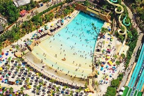 An aerial view of a resort with a large pool, multiple water slides, and a beach area with sun loungers and umbrellas. - WONDERFUL VILLA BY THE SEA IN ROME (Torvaianica)