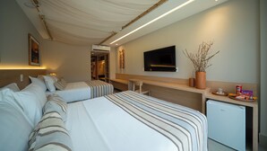 A hotel room with two beds, a desk, a TV, and a small fridge.