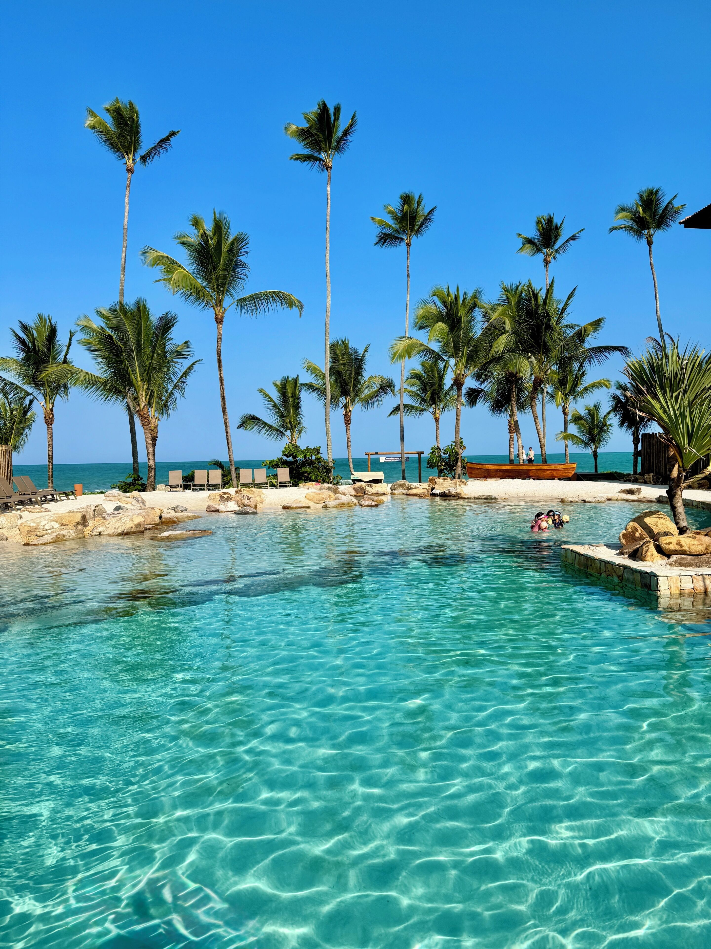 Na praia, areia branca, espreguiçadeiras, guarda-sóis 