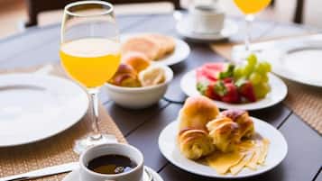 A breakfast setting with croissants, fruit, and coffee on a table.