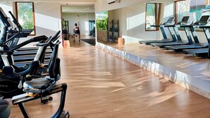 A gym with treadmills, wooden flooring, and large windows.