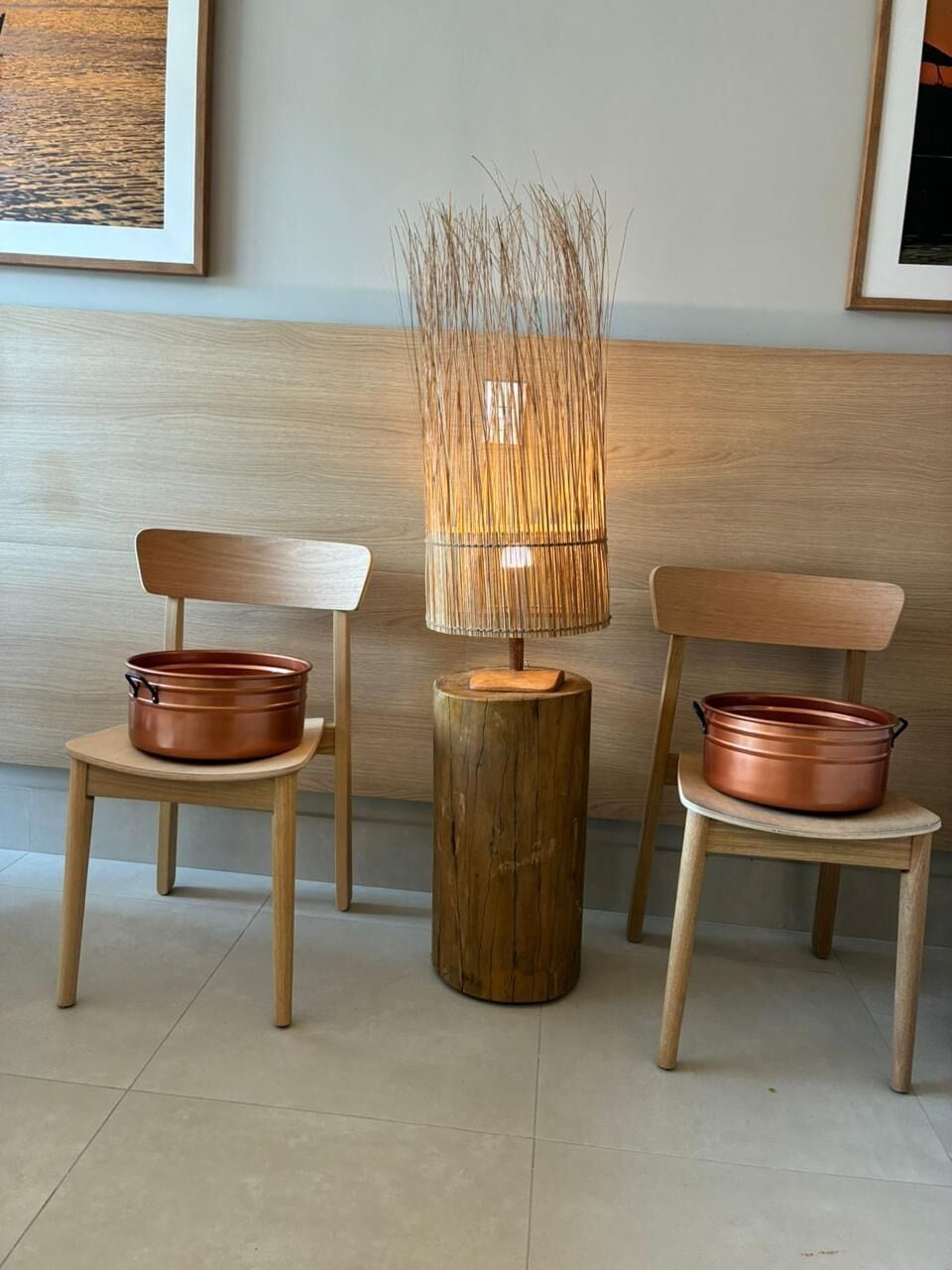 Two wooden chairs with copper pots, a bamboo lamp, and a wooden stool.