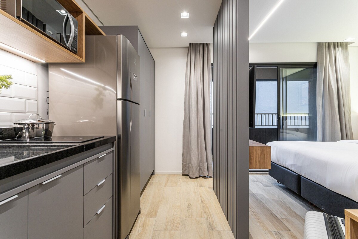 A modern kitchen with a refrigerator, a countertop, and a wooden shelf.