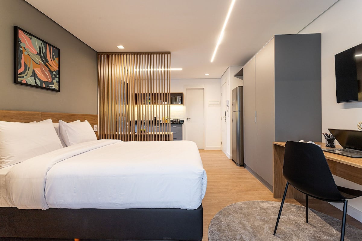 Une chambre d’hôtel moderne équipée d’un lit, d’un bureau, d’une chaise, d’une télévision et d’un panneau décoratif.