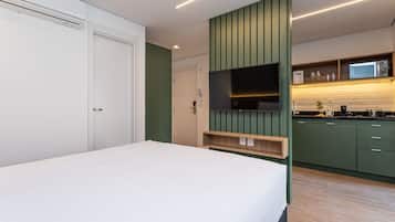 Una camera d'albergo moderna con un letto, una TV, angolo cottura e una porta.