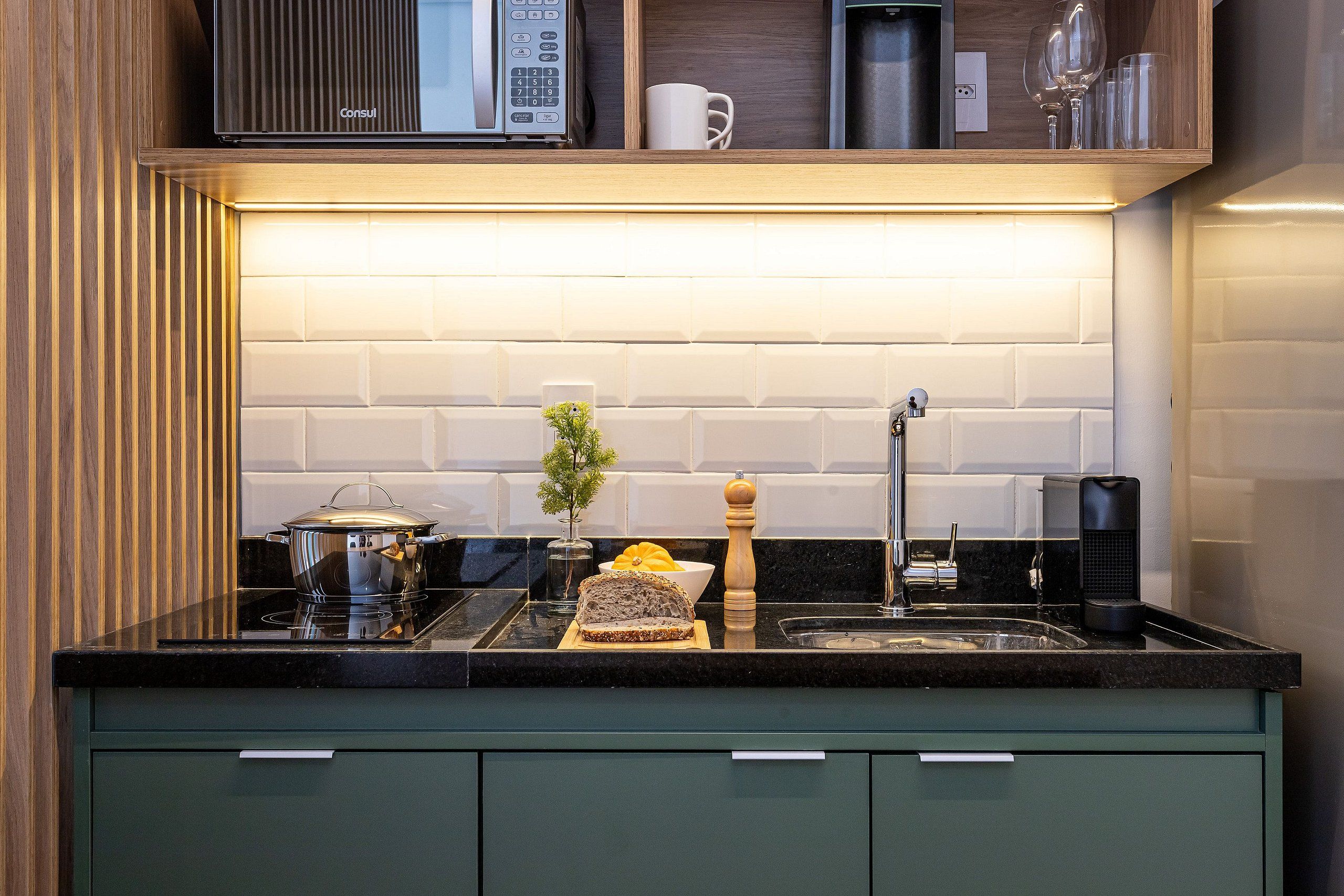 A kitchen with a black countertop, a sink, a stove, and a microwave.