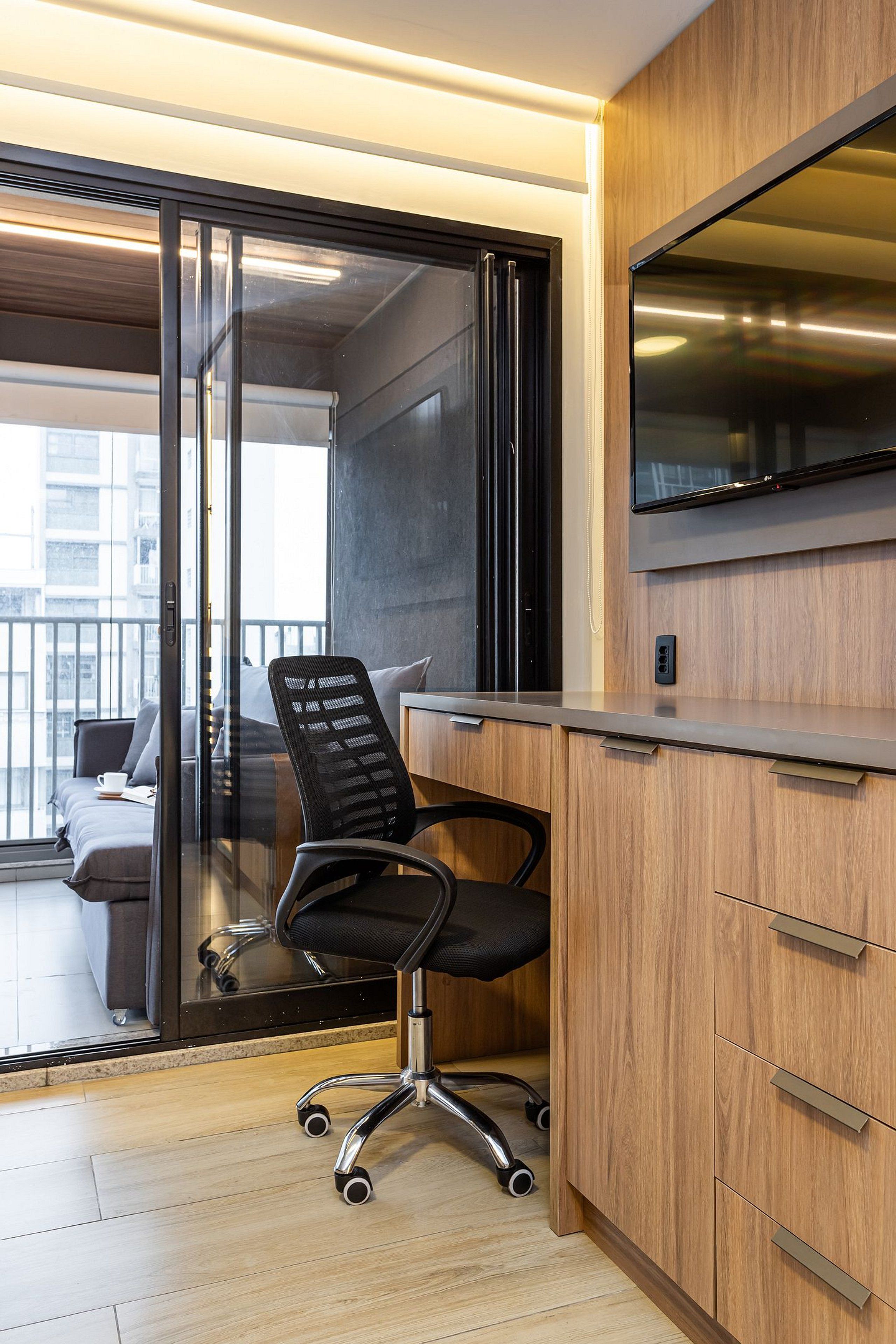 A modern office space with a desk, chair, and a large flat-screen TV mounted on the wall.