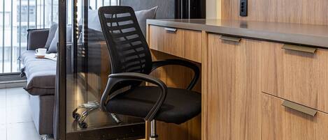 A modern office space with a desk, chair, and a large flat-screen TV mounted on the wall.