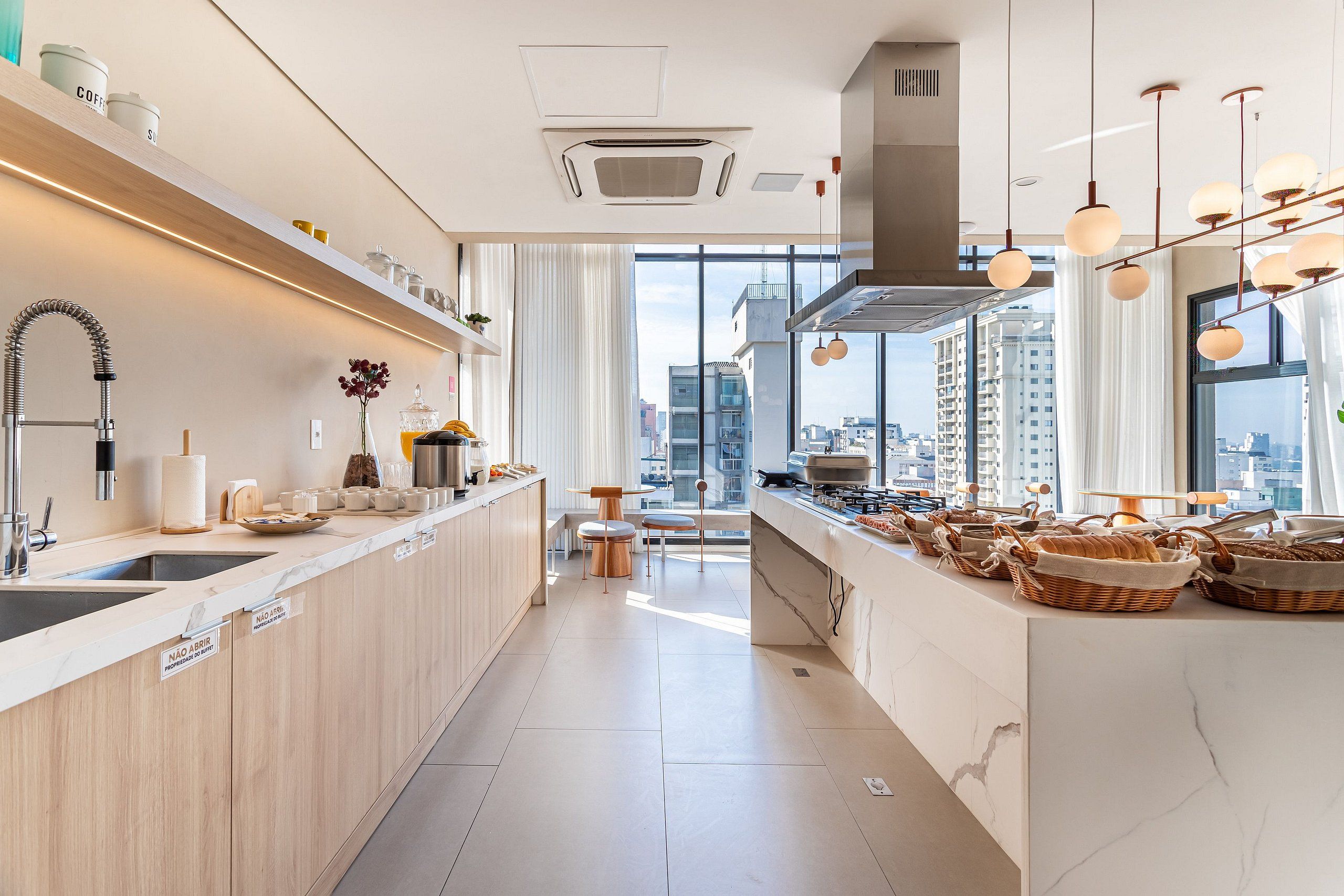 A modern kitchen with a central island, a built-in oven, and a view of the city through large windows.