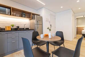 A modern kitchen with grey cabinets, a built-in microwave, and a stainless steel refrigerator. - Pivô Pamplona by Viva - Apartamentos novos e espaçosos ao lado da Av Paulista (São Paulo)