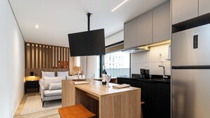 A modern kitchen with a wooden island, a built-in TV, and a stainless steel refrigerator. - Pivô Pamplona by Viva - Apartamentos novos e espaçosos ao lado da Av Paulista (São Paulo)