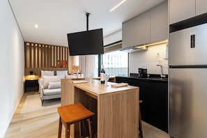 A modern kitchen with a wooden island, a built-in TV, and a stainless steel refrigerator. - Pivô Pamplona by Viva - Apartamentos novos e espaçosos ao lado da Av Paulista (São Paulo)