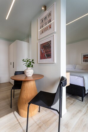 A modern room with a round wooden table, two black chairs, a potted plant, and artwork on the wall. - Pivô Pamplona by Viva - Apartamentos novos e espaçosos ao lado da Av Paulista (São Paulo)