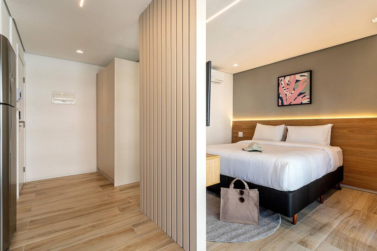 Une chambre d’hôtel moderne, équipée d’un lit, d’une table de chevet et d’une œuvre d’art accrochée au mur.