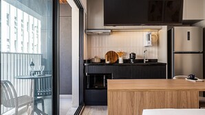 A modern kitchen with a large window, a flat-screen TV, and a wooden dining table. - Pivô Pamplona by Viva - Apartamentos novos e espaçosos ao lado da Av Paulista (São Paulo)