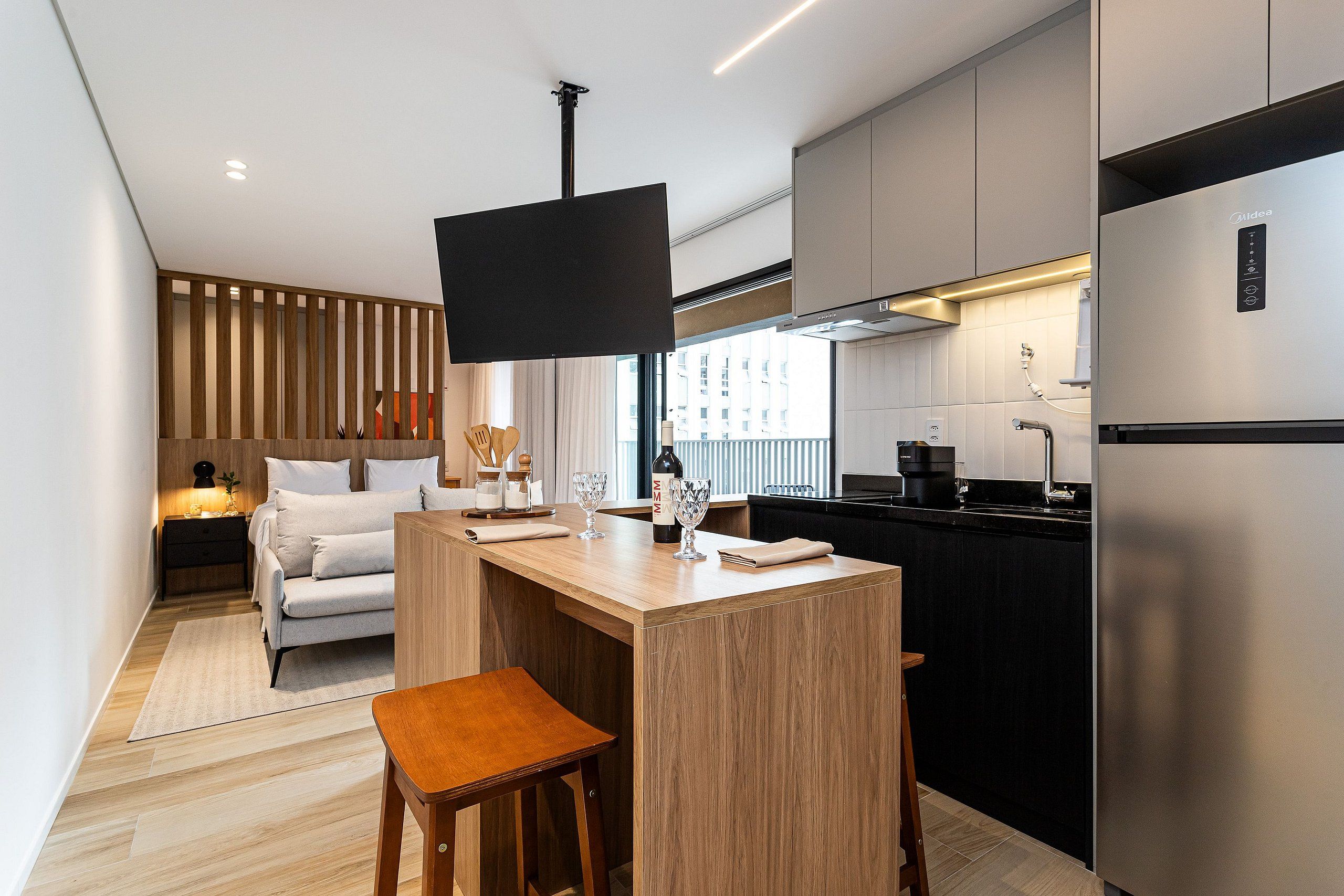 Een moderne keuken met een geïntegreerd eiland, een flatscreen televisie en een roestvrijstalen koelkast.