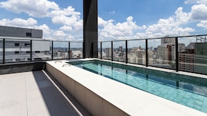 A rooftop pool with a city view, a concrete floor, and a glass railing. - Pivô Pamplona by Viva - Apartamentos novos e espaçosos ao lado da Av Paulista (São Paulo)