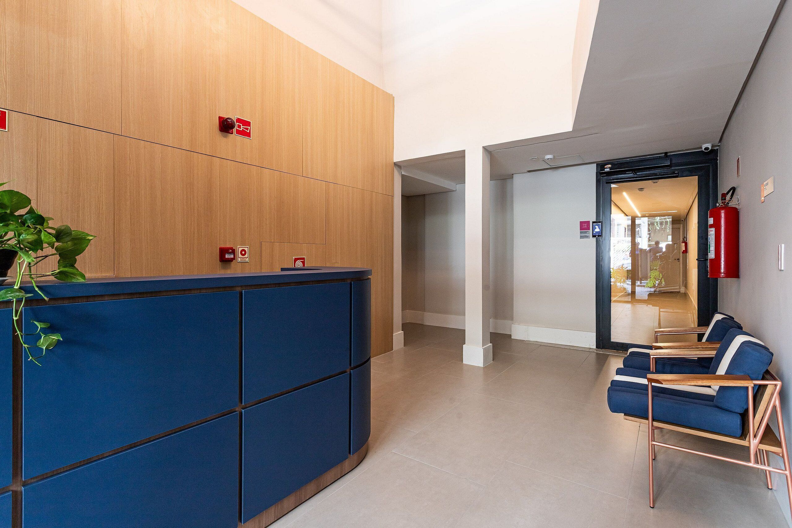 A reception area with a wooden panel wall, a blue counter, and a seating area with blue chairs.