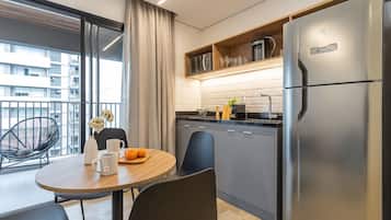 Una cocina moderna con un refrigerador grande, una mesa de comedor con sillas y vistas a la ciudad a través de amplios ventanales.