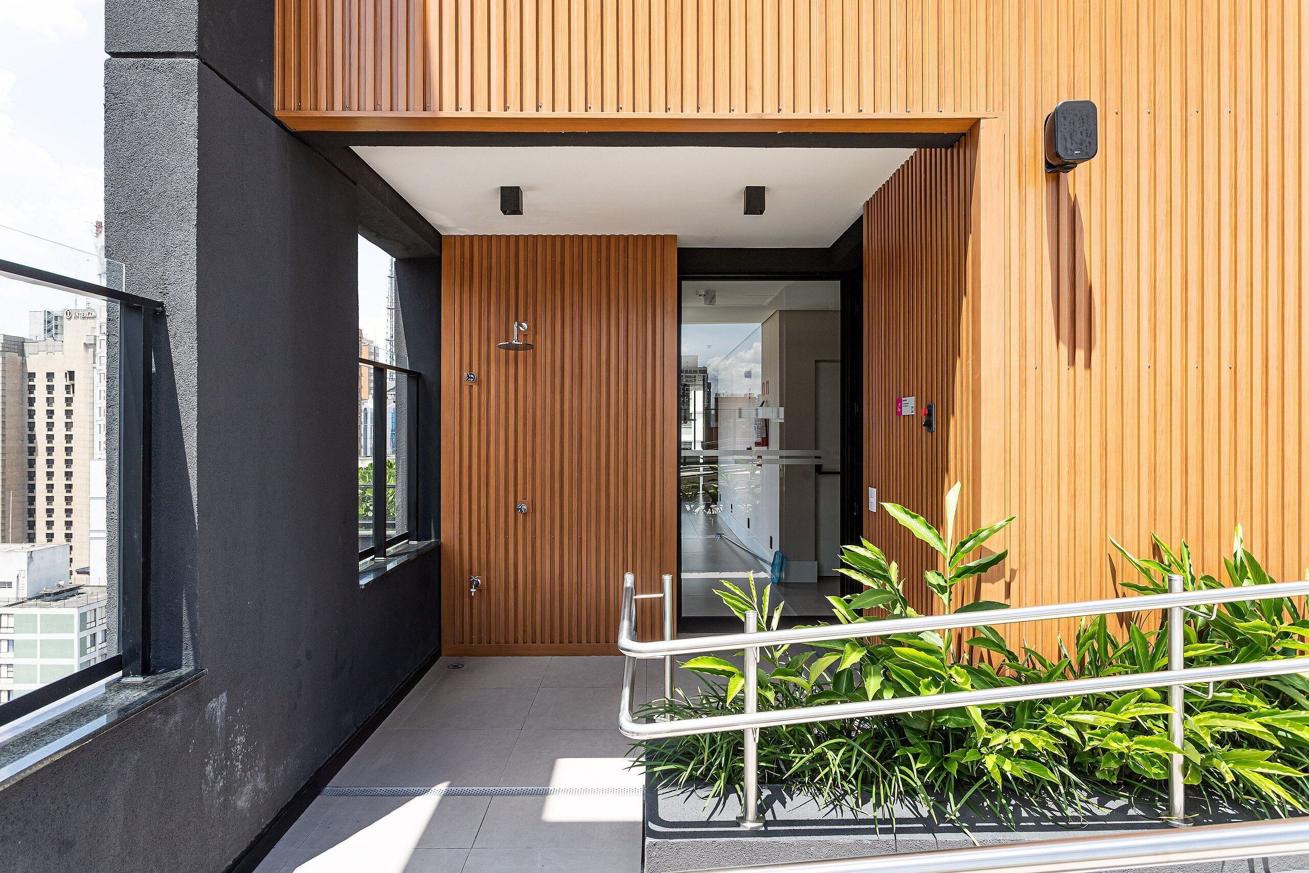 A modern building with a black exterior, wooden accents, and a balcony with metal railings.