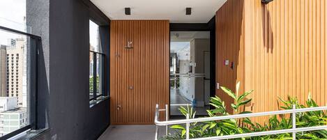 A modern building with a black exterior, wooden accents, and a balcony with metal railings.