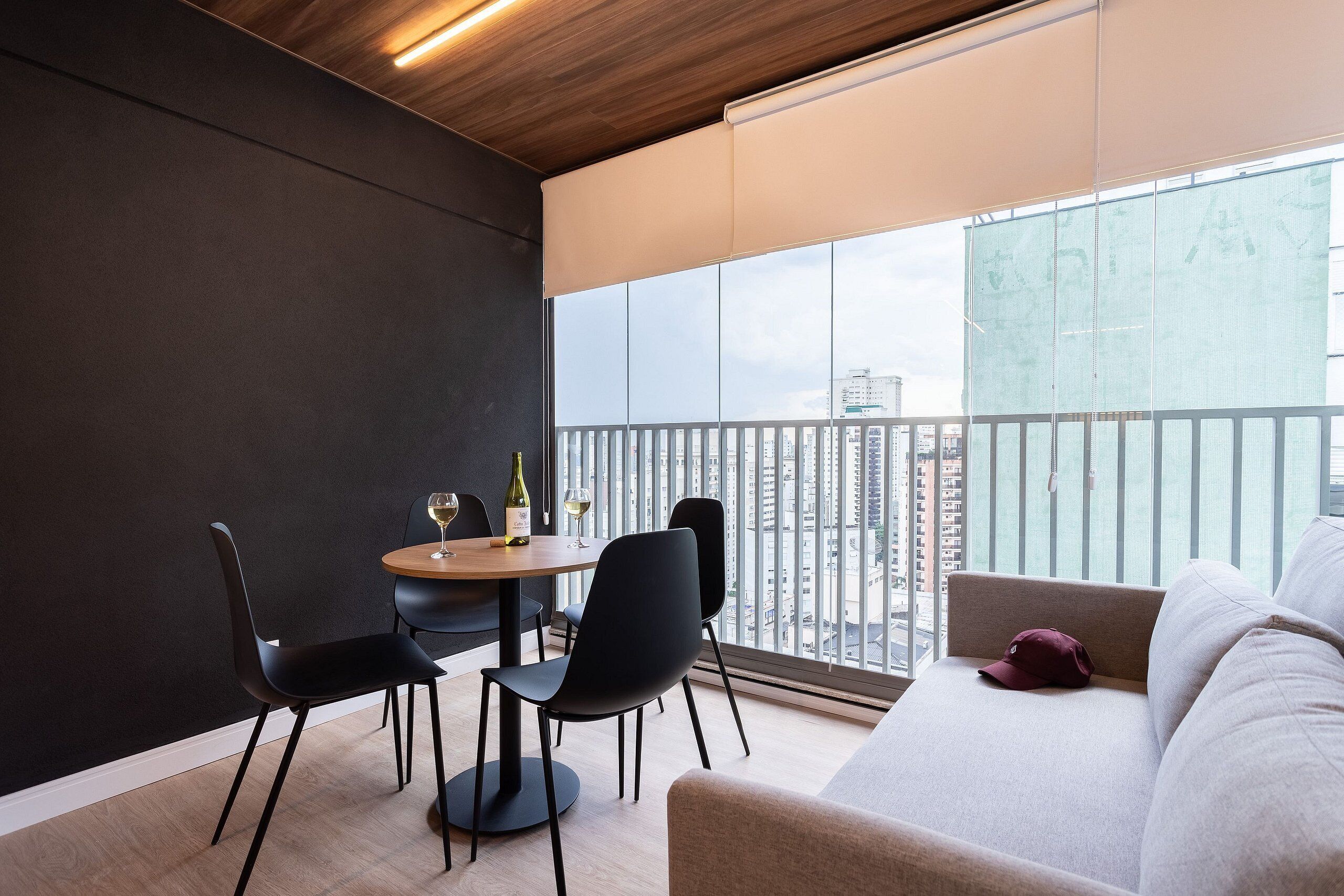 A modern room with a balcony, a dining table with chairs, and a sofa.