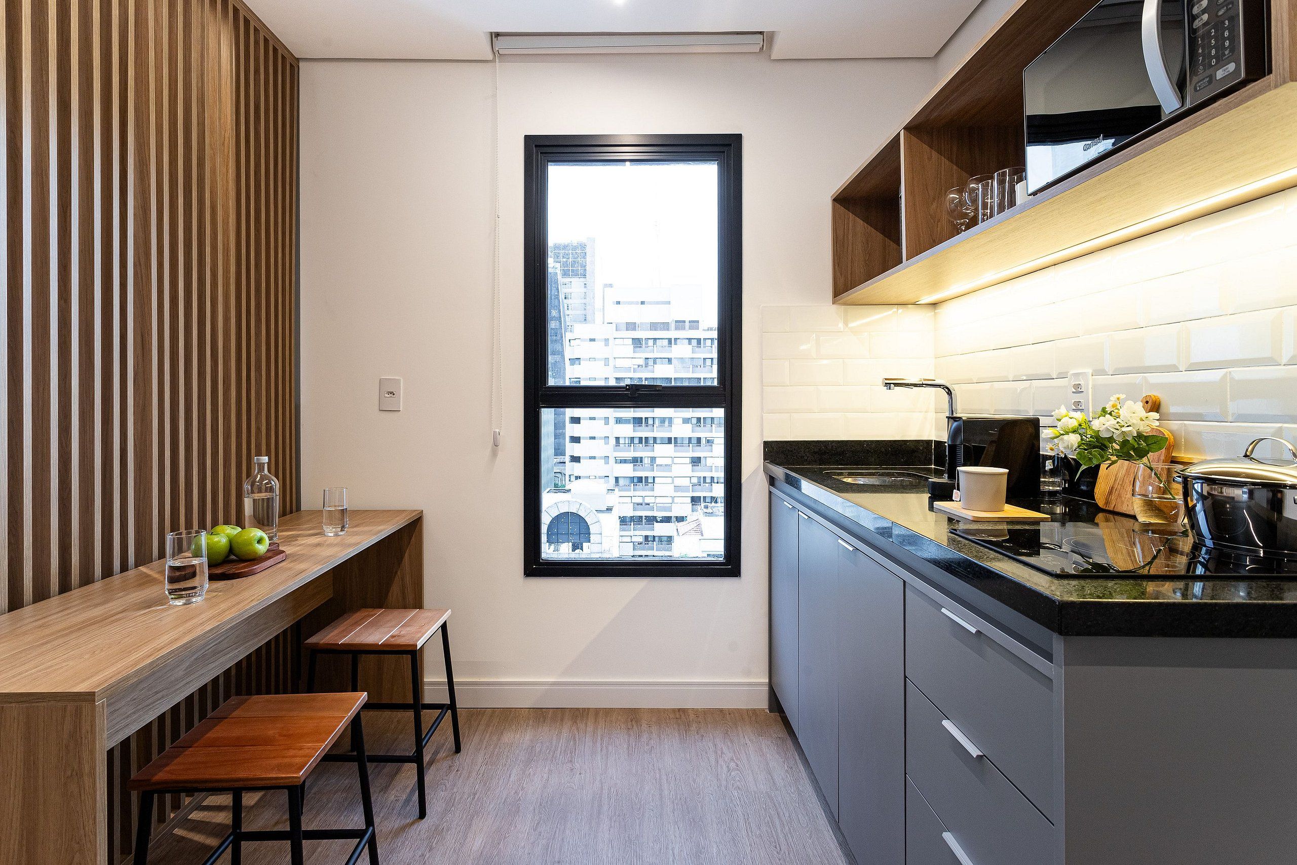 A modern kitchen with a wooden countertop, a window, and a view of buildings.
