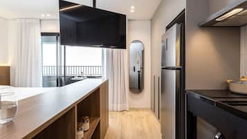 A modern kitchen with a built-in oven, a large flat-screen TV, and a wooden countertop.