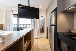 A modern kitchen with a built-in oven, a large flat-screen TV, and a wooden countertop. - Pivô Pamplona by Viva - Apartamentos novos e espaçosos ao lado da Av Paulista (São Paulo)