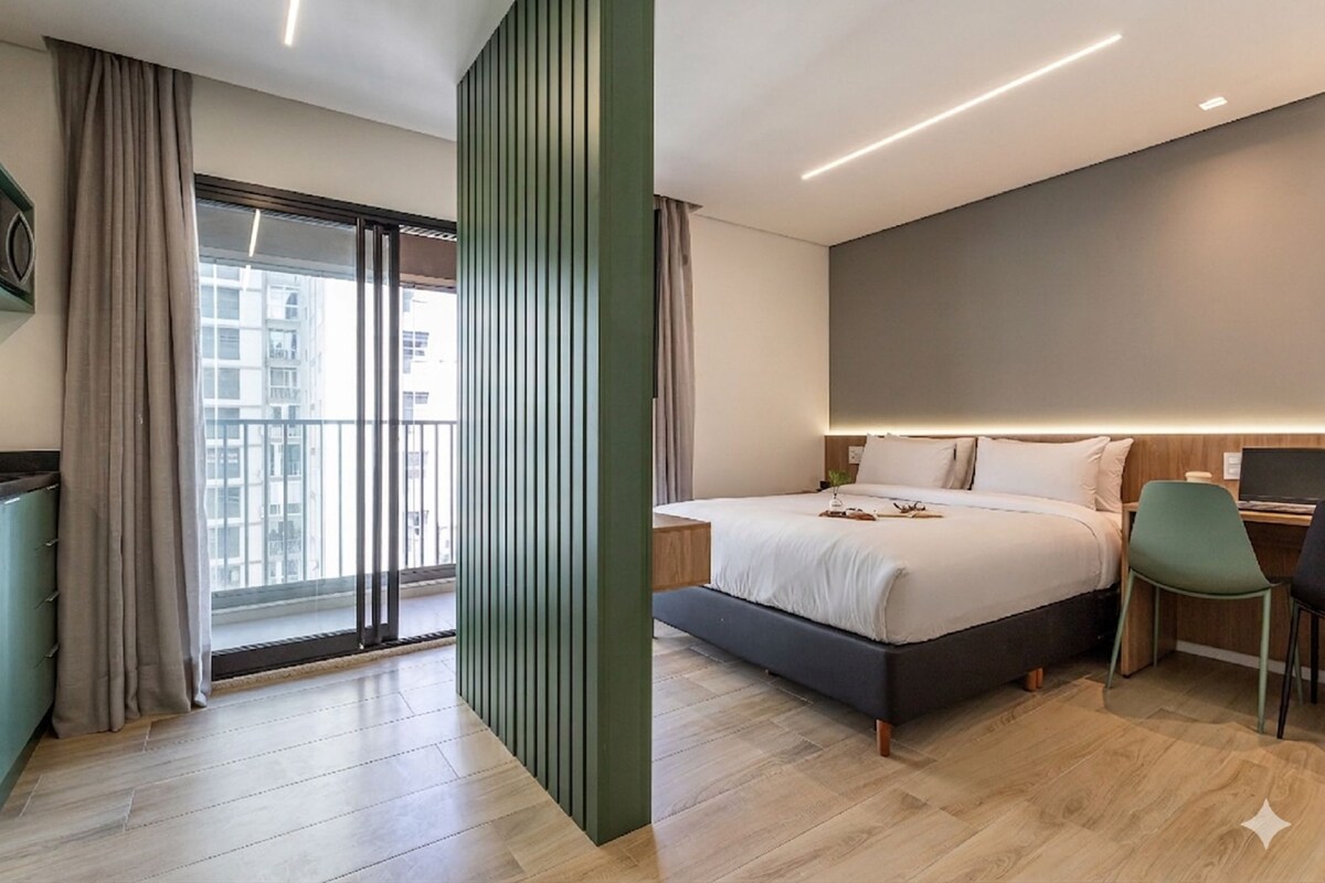 A modern hotel room with a large bed, a desk, and a view of the city.