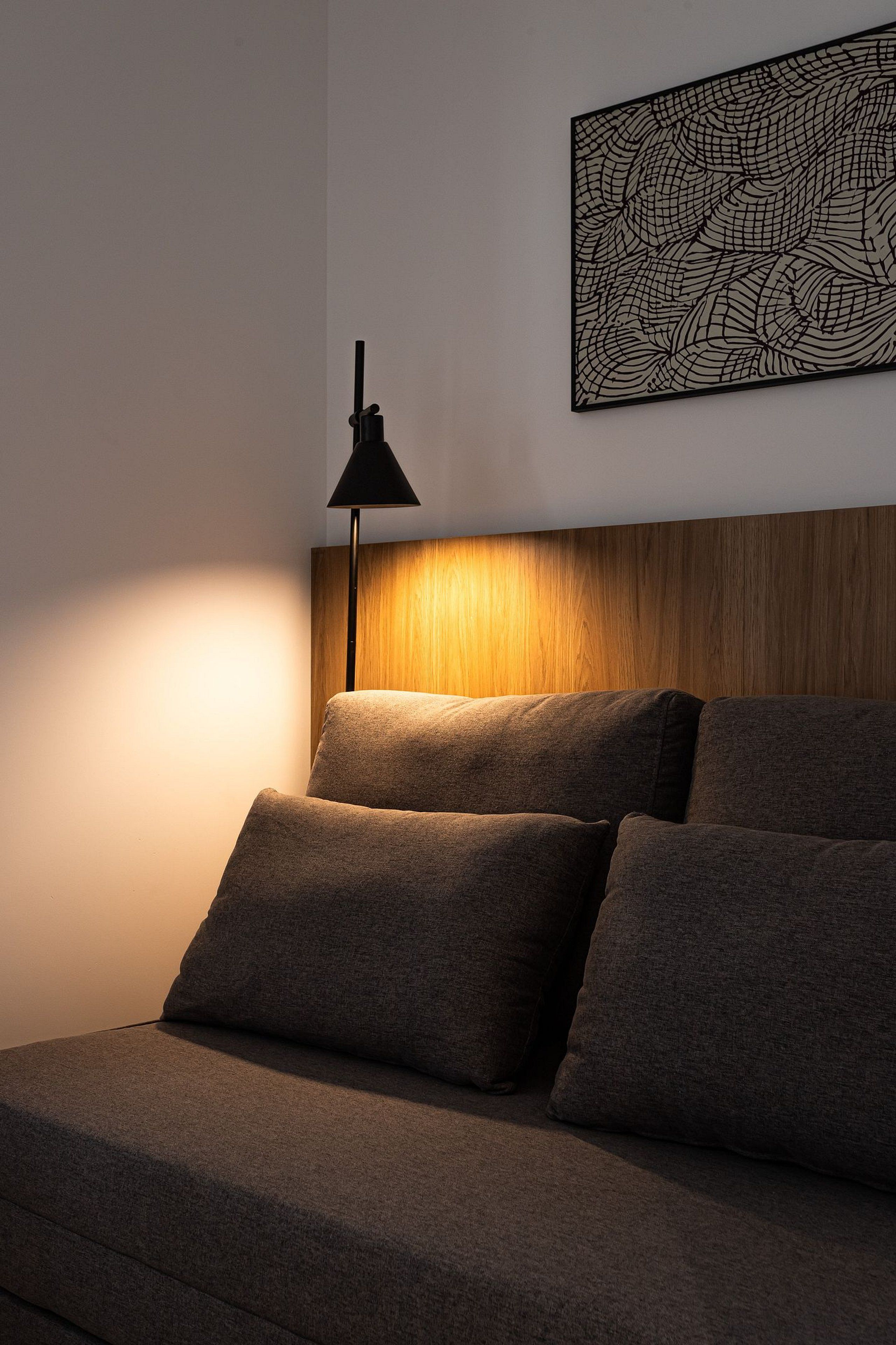 Ein Bett mit Kopfteil, ein Wandbild und eine Stehlampe.