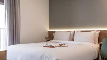 A neatly made bed with a tray of breakfast items, a book, and glasses on the bedside table.